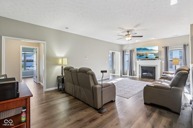 1209 E Wabash St, Frankfort, IN 46041 - living room featuring wood finished floors, a ceiling fan, a textured ceiling, and a glass covered fireplace