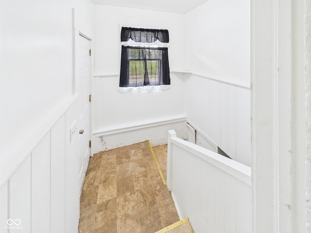 1201 Arrow Ave, Anderson, IN 46016 - corridor with a decorative wall, an upstairs landing, a wainscoted wall, and light stone finish floors