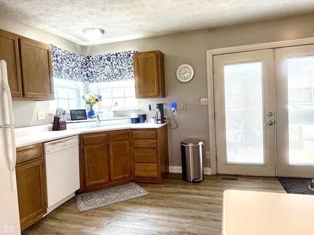 4065 W New Castle Rd, Frankfort, IN 46041 - kitchen featuring white appliances, brown cabinetry, light countertops, light wood-type flooring, and a textured ceiling
