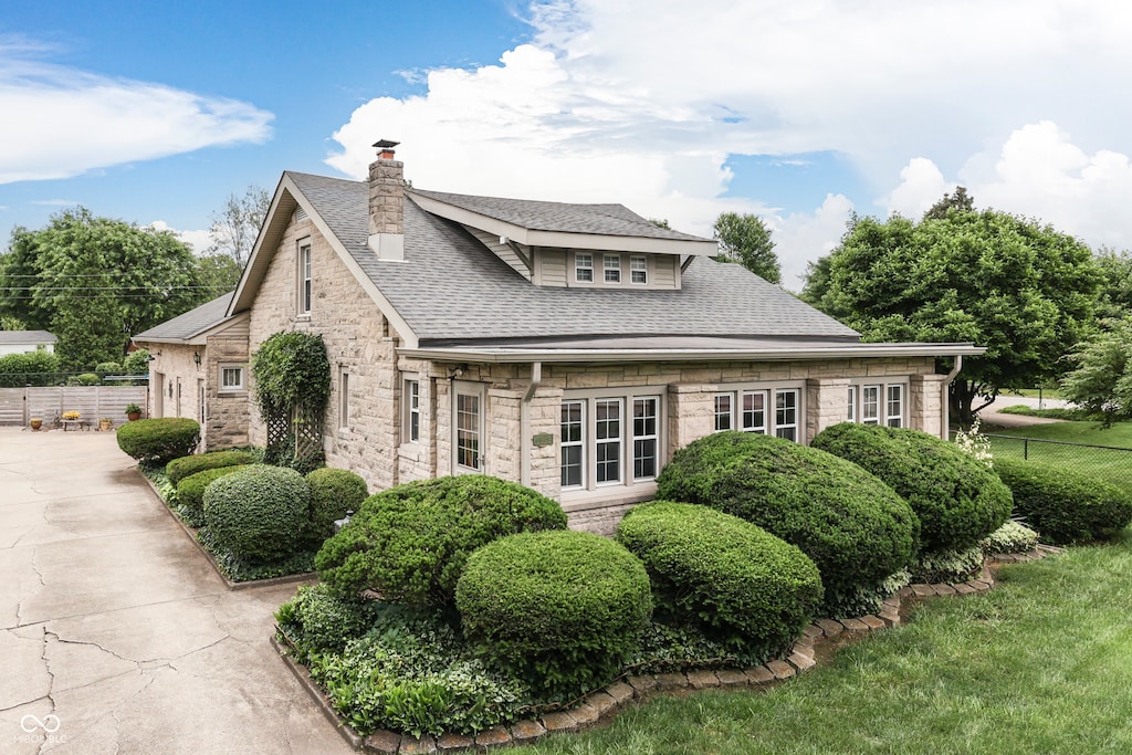 6649 Madison Ave, Indianapolis, IN 46227 - view of home's exterior featuring roof with shingles, stone siding, and a chimney