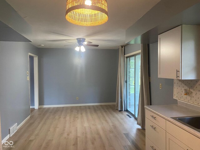 8008 Cherington Dr, Indianapolis, IN 46227 - kitchen featuring light wood-type flooring, white cabinets, ceiling fan, and backsplash