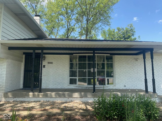 8008 Cherington Dr, Indianapolis, IN 46227 - entrance to property featuring a porch, brick siding, and a chimney