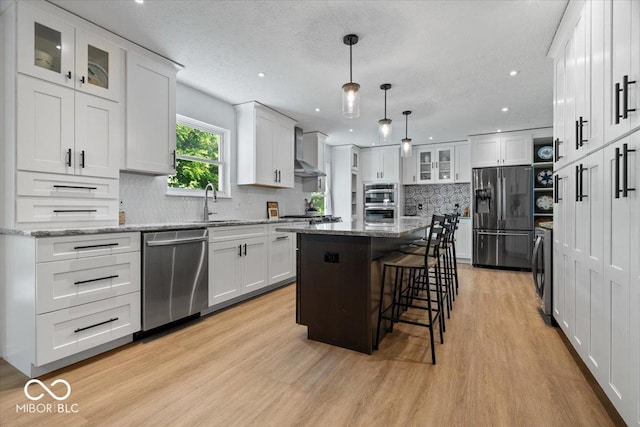 8827 Lindsey Ct, Fishers, IN 46038 - kitchen with appliances with stainless steel finishes, wall chimney range hood, light wood-style floors, white cabinets, and a kitchen island