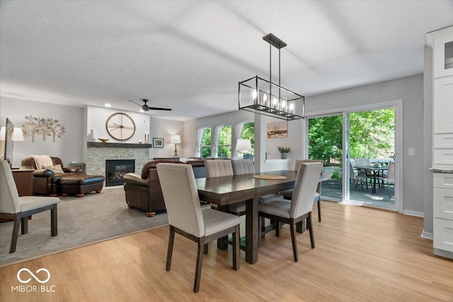 8827 Lindsey Ct, Fishers, IN 46038 - dining area featuring light wood finished floors, a ceiling fan, plenty of natural light, a fireplace, and a textured ceiling