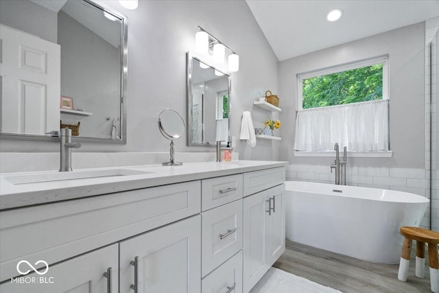 8827 Lindsey Ct, Fishers, IN 46038 - full bath with double vanity, a soaking tub, wood finished floors, tile walls, and recessed lighting