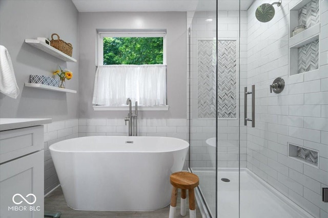 8827 Lindsey Ct, Fishers, IN 46038 - bathroom with a freestanding tub, vanity, a shower stall, a wainscoted wall, and tile walls