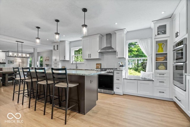 8827 Lindsey Ct, Fishers, IN 46038 - kitchen featuring wall chimney range hood, stainless steel appliances, a center island, light wood-style floors, and recessed lighting