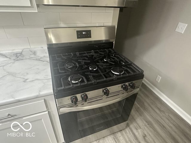 1306 Woodbine Dr, Anderson, IN 46011 - kitchen view of stainless steel gas range, tasteful backsplash, light wood-type flooring, white cabinets, and light countertops