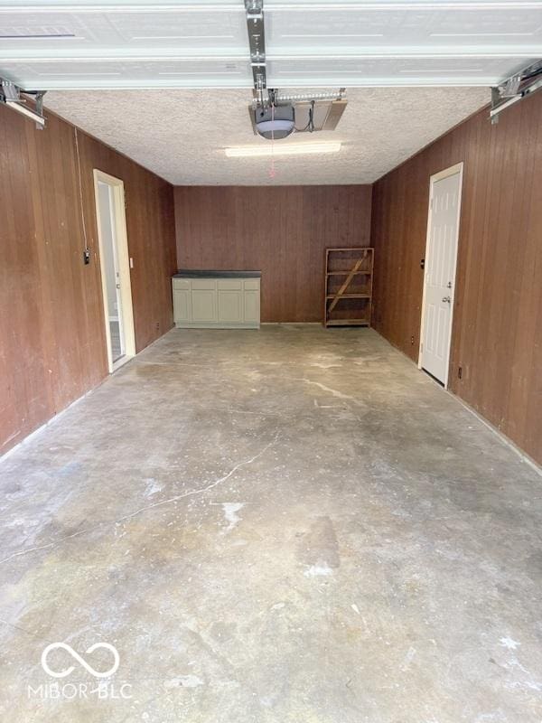 1306 Woodbine Dr, Anderson, IN 46011 - garage featuring wooden walls and a garage door opener