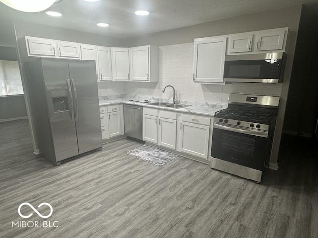 1306 Woodbine Dr, Anderson, IN 46011 - kitchen featuring appliances with stainless steel finishes, light wood-type flooring, white cabinets, and decorative backsplash