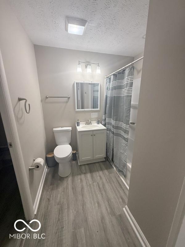1306 Woodbine Dr, Anderson, IN 46011 - full bathroom featuring a textured ceiling, wood finished floors, and vanity