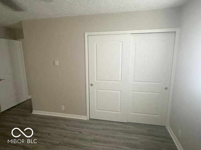 1306 Woodbine Dr, Anderson, IN 46011 - unfurnished bedroom featuring dark wood-type flooring, a textured ceiling, and a closet