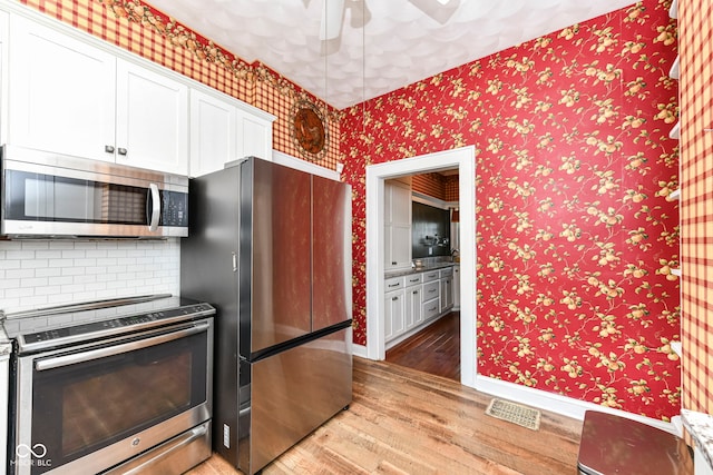 1325 Fordice Rd, Lebanon, IN 46052 - kitchen featuring stainless steel appliances, light wood-style flooring, white cabinets, wallpapered walls, and ceiling fan