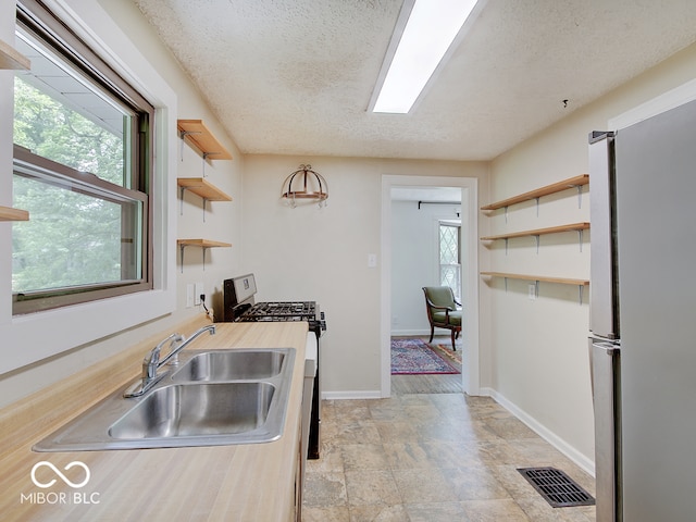 1908 W Northgate St, Indianapolis, IN 46228 - kitchen with open shelves, stainless steel appliances, stone finish flooring, a textured ceiling, and wooden counters