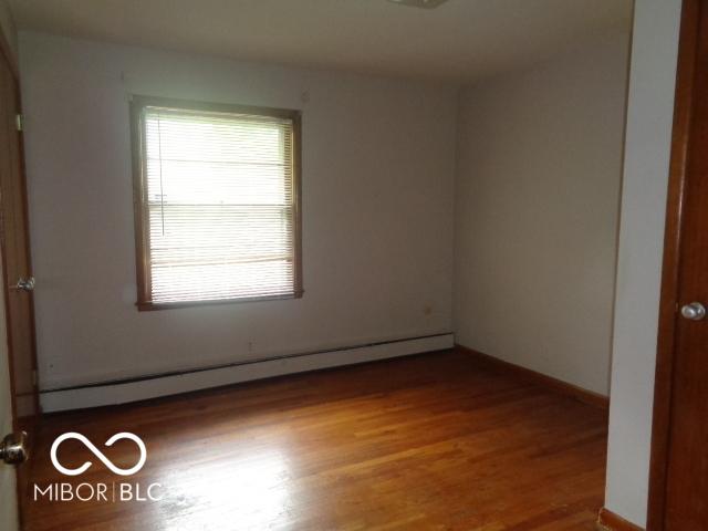 3253 W 34th St, Indianapolis, IN 46222 - unfurnished room featuring a baseboard heating unit and wood finished floors