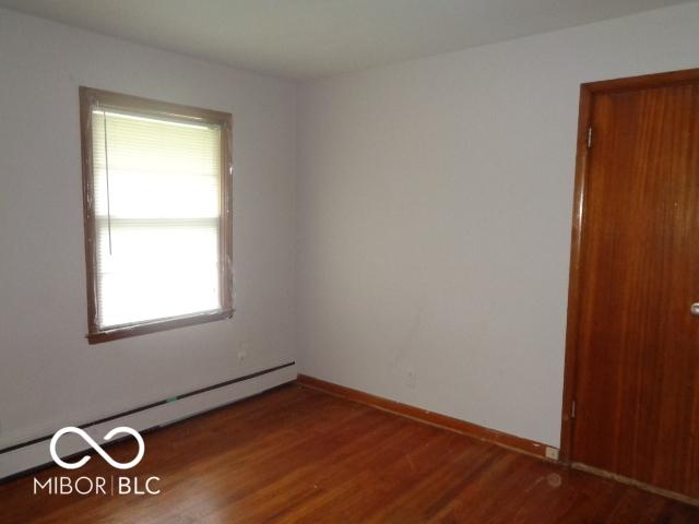 3253 W 34th St, Indianapolis, IN 46222 - unfurnished room featuring a baseboard heating unit and wood finished floors