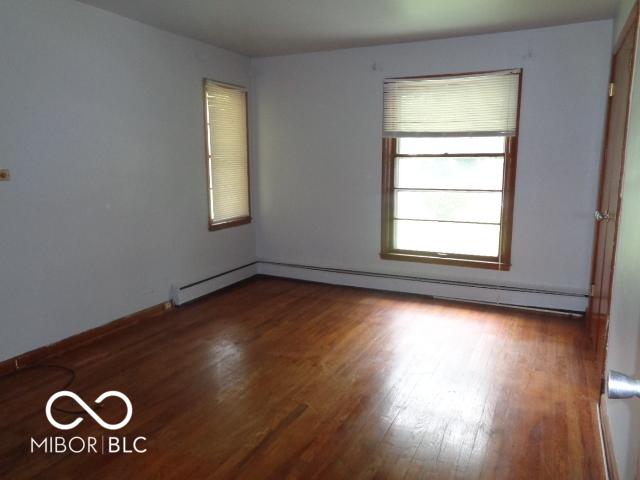 3253 W 34th St, Indianapolis, IN 46222 - empty room with baseboard heating and wood finished floors
