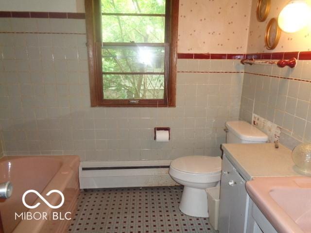 3253 W 34th St, Indianapolis, IN 46222 - full bath featuring tile walls, a baseboard heating unit, vanity, a tub, and wainscoting