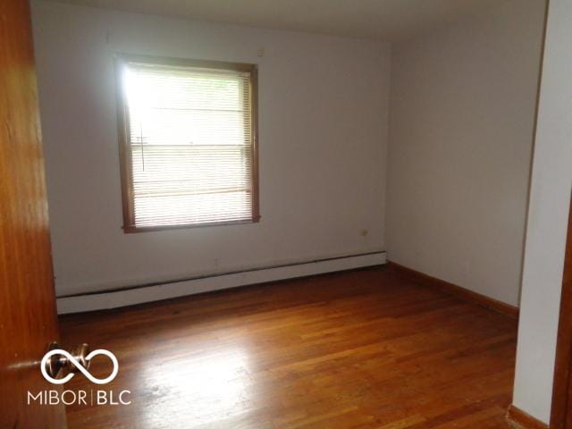 3253 W 34th St, Indianapolis, IN 46222 - unfurnished room featuring a baseboard heating unit and wood finished floors