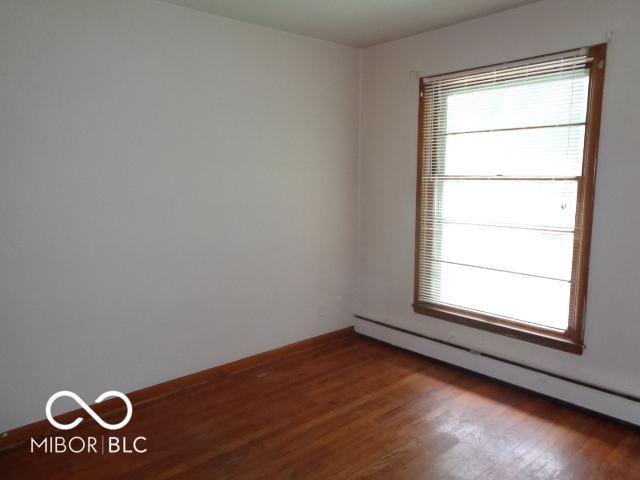 3253 W 34th St, Indianapolis, IN 46222 - spare room with a baseboard heating unit and wood finished floors