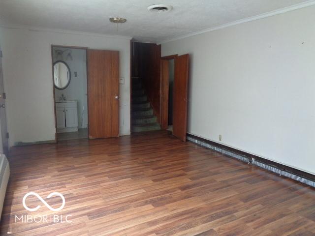 3253 W 34th St, Indianapolis, IN 46222 - empty room featuring light wood-type flooring, ornamental molding, and stairway
