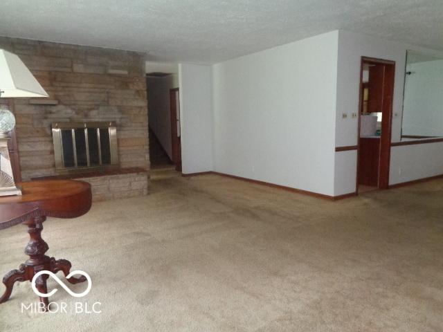 3253 W 34th St, Indianapolis, IN 46222 - unfurnished living room with a fireplace, carpet flooring, and a textured ceiling