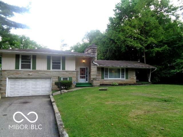 3253 W 34th St, Indianapolis, IN 46222 - view of front of house with asphalt driveway, stone siding, a garage, and a front yard