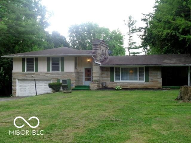 3253 W 34th St, Indianapolis, IN 46222 - split level home with an attached garage, a chimney, a front yard, stone siding, and asphalt driveway