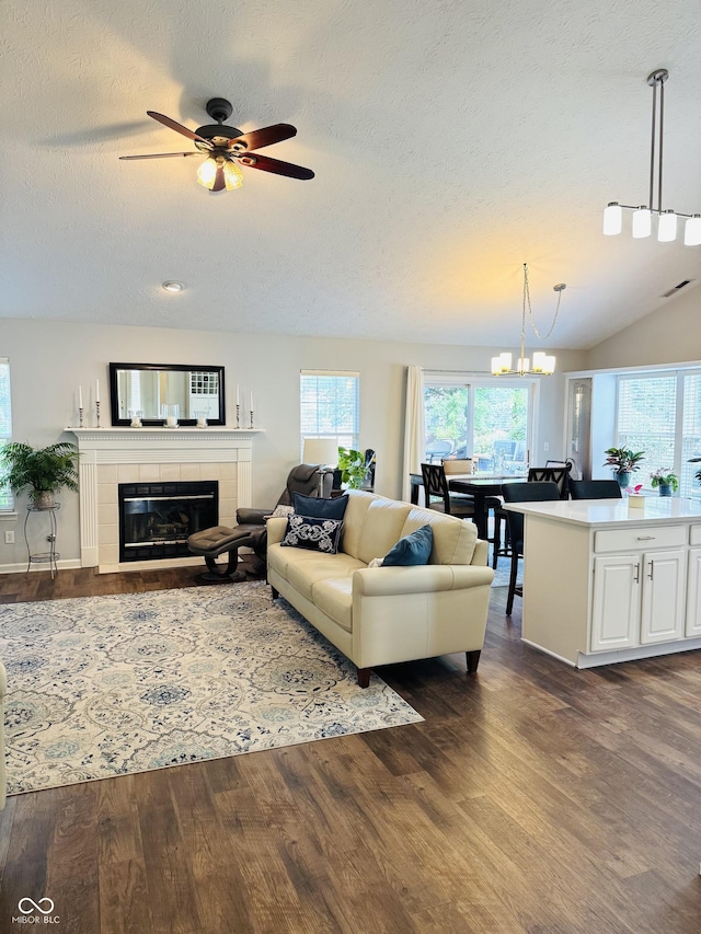10477 Silver Ridge Cir, Fishers, IN 46038 - living room with dark wood-type flooring, a tile fireplace, a textured ceiling, a ceiling fan, and a chandelier