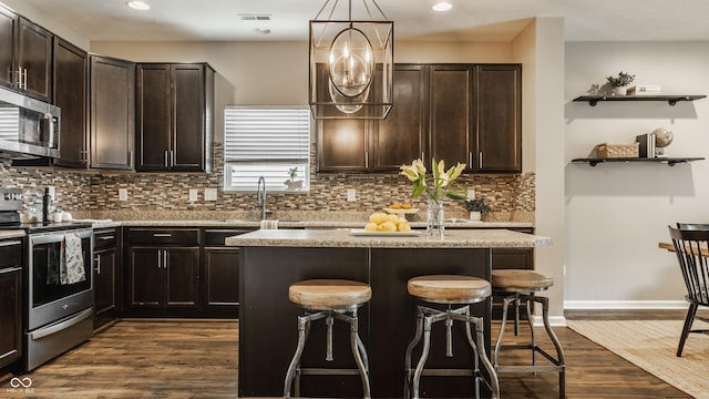 17183 Petersfield Ln, Westfield, IN 46074 - kitchen featuring appliances with stainless steel finishes, a kitchen bar, dark brown cabinetry, a kitchen island, and recessed lighting