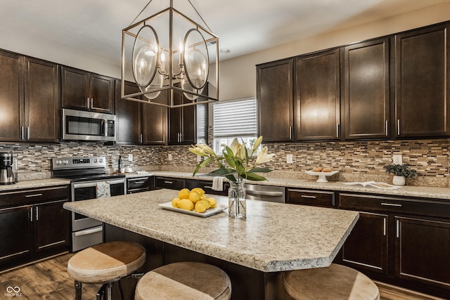 17183 Petersfield Ln, Westfield, IN 46074 - kitchen with appliances with stainless steel finishes, a kitchen breakfast bar, dark brown cabinetry, and a center island