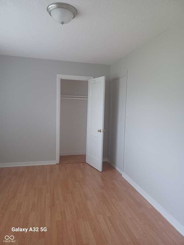 2138 Admiral Dr, Indianapolis, IN 46219 - unfurnished bedroom with light wood-style flooring, a closet, and a textured ceiling