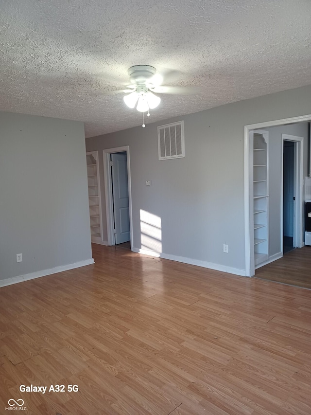 2138 Admiral Dr, Indianapolis, IN 46219 - unfurnished room featuring ceiling fan, built in shelves, a textured ceiling, and light wood-type flooring