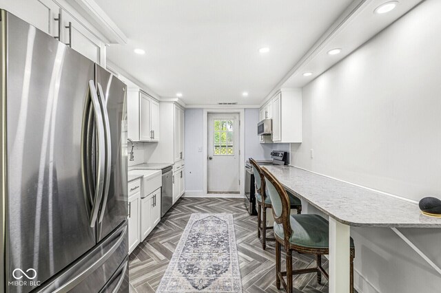 777 Sycamore St, Westfield, IN 46074 - kitchen featuring appliances with stainless steel finishes, white cabinetry, recessed lighting, a kitchen breakfast bar, and light stone counters
