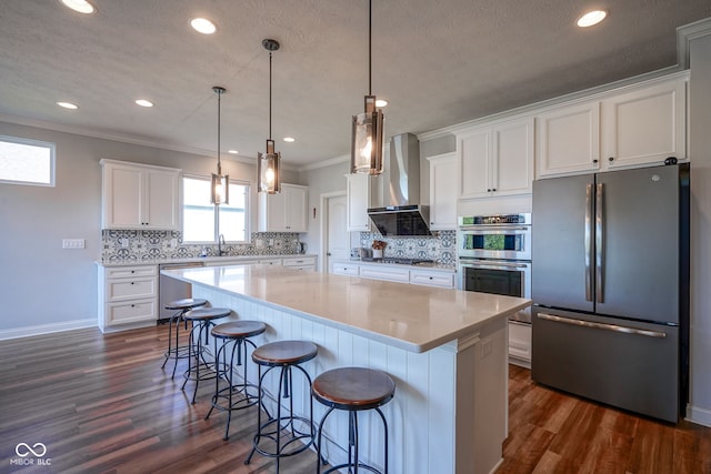 16235 Natures Way, Westfield, IN 46074 - kitchen featuring stainless steel appliances, wall chimney range hood, a kitchen island, white cabinets, and crown molding