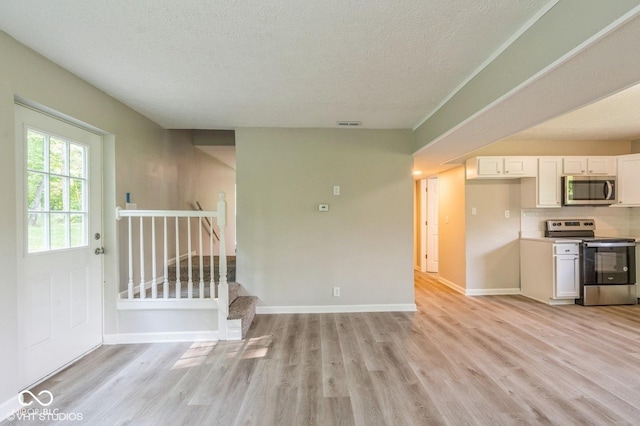 6570 N Private Road 525 E, North Vernon, IN 47265 - kitchen featuring appliances with stainless steel finishes, light wood-type flooring, white cabinetry, a textured ceiling, and tasteful backsplash