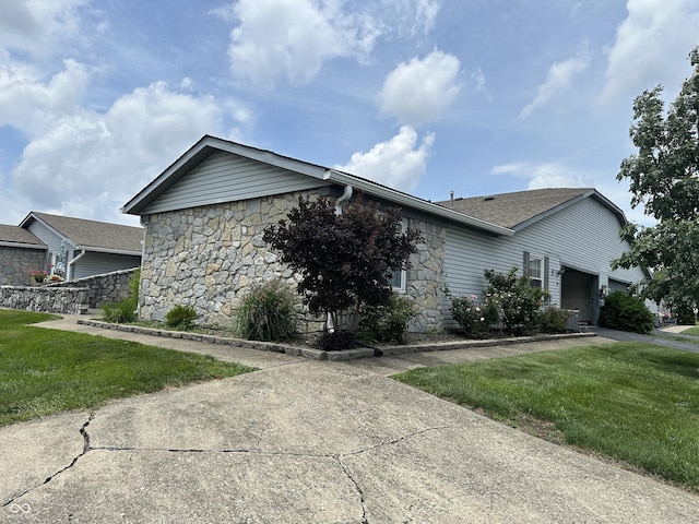1001 Paradise Ct Unit F, Greenwood, IN 46143 - view of side of home with stone siding, a yard, an attached garage, and driveway