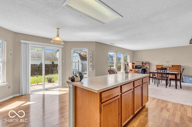 2309 Westmere Dr, Plainfield, IN 46168 - kitchen featuring a textured ceiling, light wood-style flooring, light countertops, decorative light fixtures, and a center island