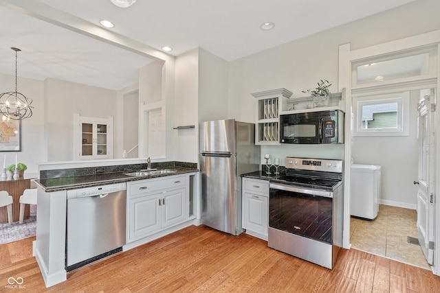 2026 E 10th St, Indianapolis, IN 46201 - kitchen featuring stainless steel appliances, a peninsula, light wood-style flooring, dark stone countertops, and a chandelier