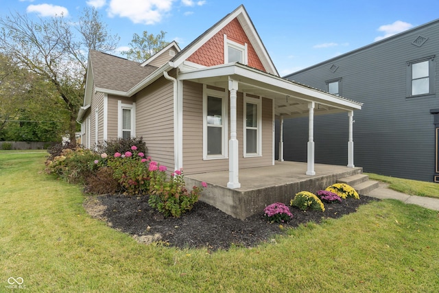 2026 E 10th St, Indianapolis, IN 46201 - view of side of property featuring covered porch, a yard, and a shingled roof