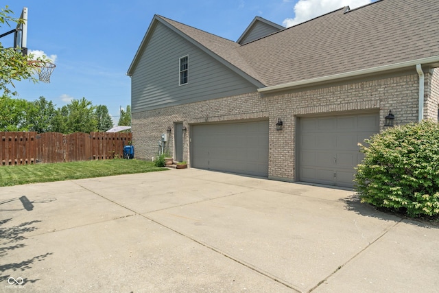 8754 Lily Ct, Zionsville, IN 46077 - view of side of property with brick siding, concrete driveway, a shingled roof, and a garage