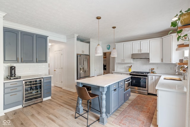 8754 Lily Ct, Zionsville, IN 46077 - kitchen featuring beverage cooler, appliances with stainless steel finishes, a breakfast bar area, under cabinet range hood, and decorative backsplash