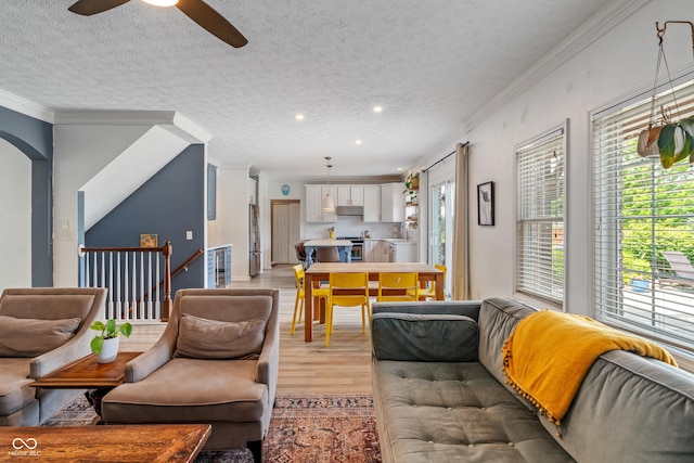 8754 Lily Ct, Zionsville, IN 46077 - living room featuring light wood-style floors, ornamental molding, plenty of natural light, a ceiling fan, and a textured ceiling