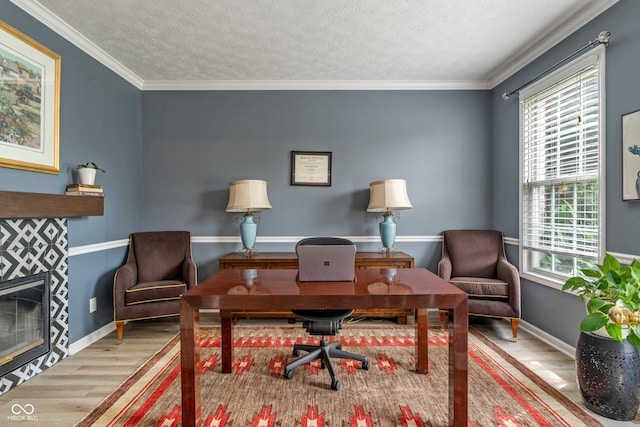8754 Lily Ct, Zionsville, IN 46077 - office area featuring wood finished floors, a tiled fireplace, a textured ceiling, and ornamental molding
