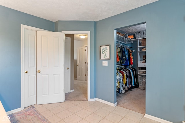 8754 Lily Ct, Zionsville, IN 46077 - bedroom with light carpet, a closet, a spacious closet, light tile patterned floors, and a textured ceiling