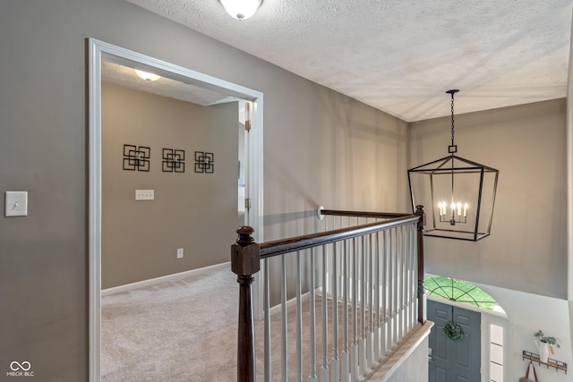 8754 Lily Ct, Zionsville, IN 46077 - hallway with a textured ceiling, a chandelier, an upstairs landing, and carpet floors