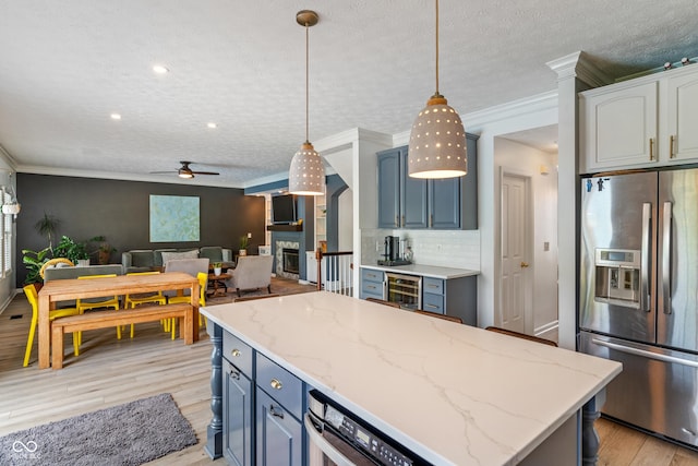 8754 Lily Ct, Zionsville, IN 46077 - kitchen with stainless steel fridge, ceiling fan, a fireplace, light wood-style flooring, and backsplash