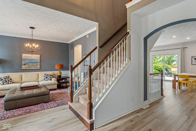 8754 Lily Ct, Zionsville, IN 46077 - living room with arched walkways, wood finished floors, a textured ceiling, a chandelier, and ornamental molding