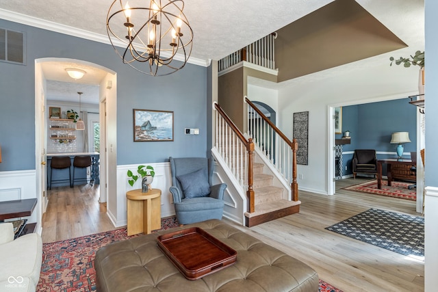 8754 Lily Ct, Zionsville, IN 46077 - stairs featuring arched walkways, wood finished floors, ornamental molding, a chandelier, and a textured ceiling