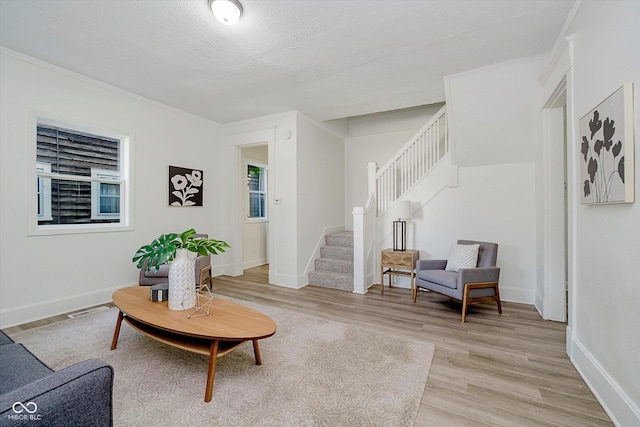 3709 Central Ave, Indianapolis, IN 46205 - living room featuring stairs, light wood-style flooring, ornamental molding, and a textured ceiling